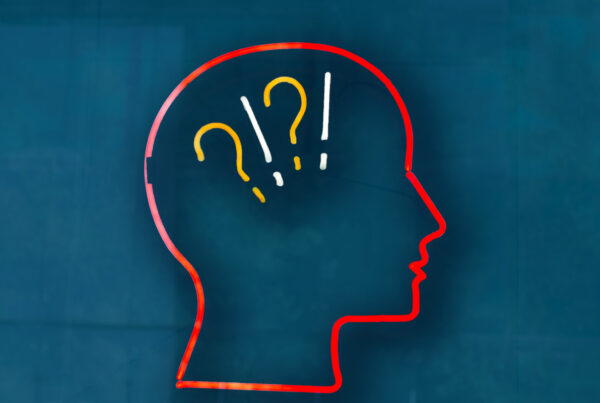 Neon sign of a human head with question marks and exclamation points.